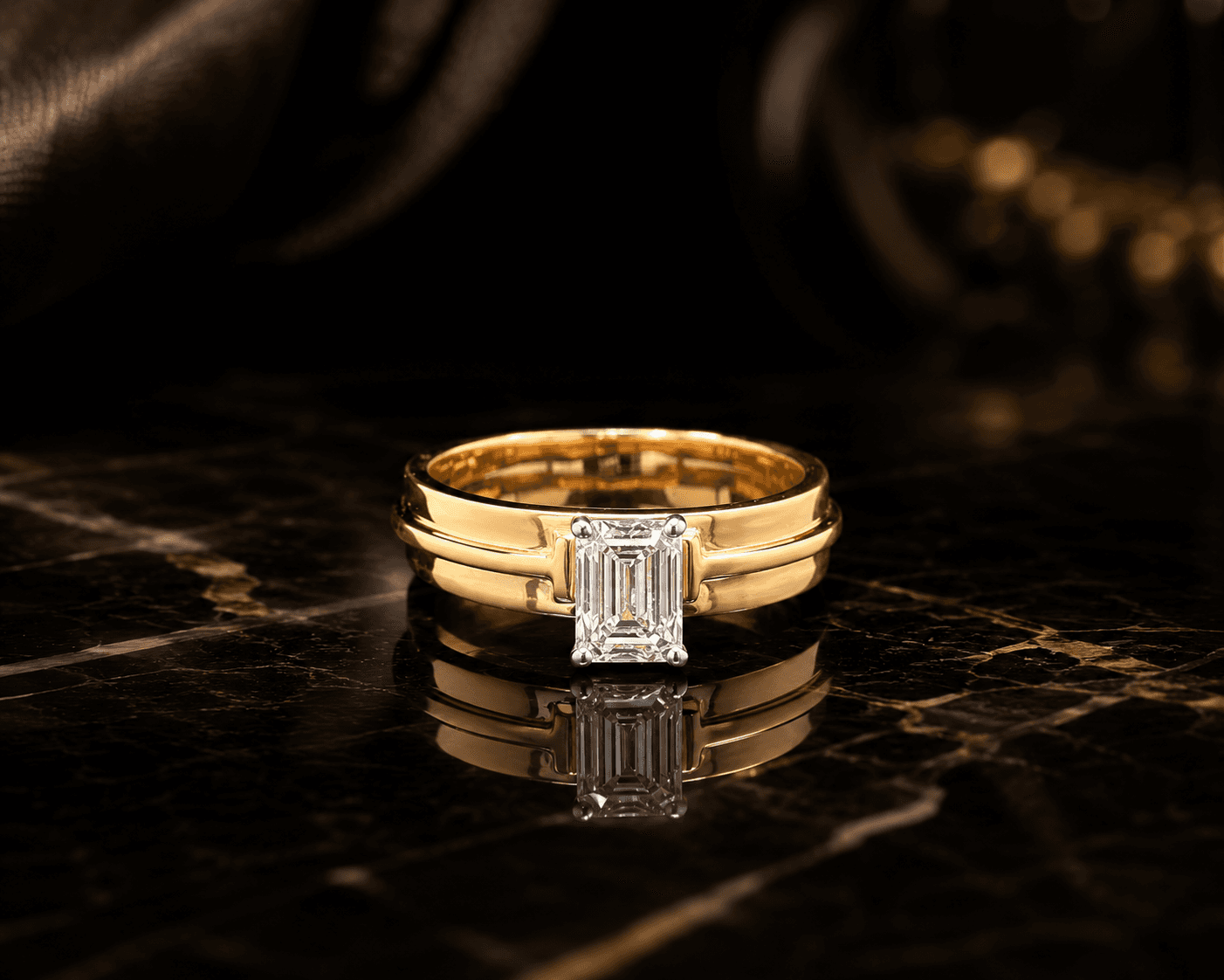 A solitaire emerald-cut lab-grown diamond set flush into a broad yellow gold band, on dark marble.